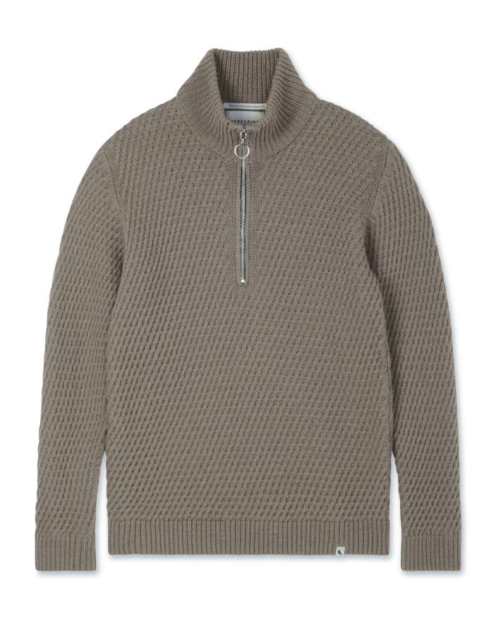 A taupe-colored, long-sleeve sweater featuring a textured knit pattern and a half-zip front with a circular zipper pull. It has a high, ribbed collar and ribbed cuffs and hem.