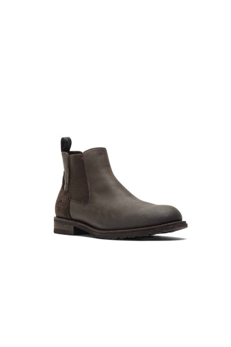 A brown leather Chelsea boot with elastic side panels and a pull tab at the back. The boot has a low heel and a rounded toe, with a slightly textured sole for grip.