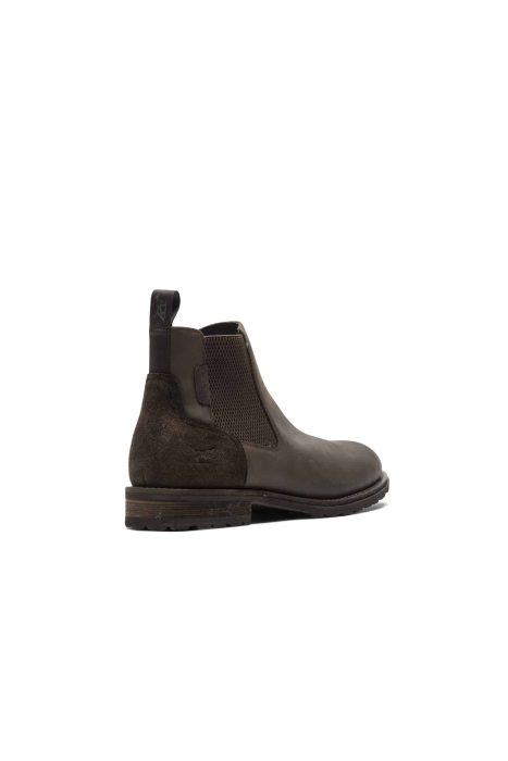 A single brown Chelsea boot with a suede and leather finish is shown. It has a low wooden heel and a pull-tab at the back for easy wearing. The boot is positioned on a plain white background with a slight angle to display the side view.