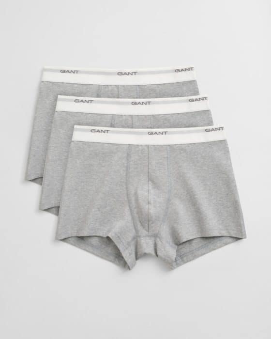 Three pairs of gray boxer briefs with white elastic waistbands, each displaying the brand name GANT in black lettering, are neatly stacked against a light gray background.