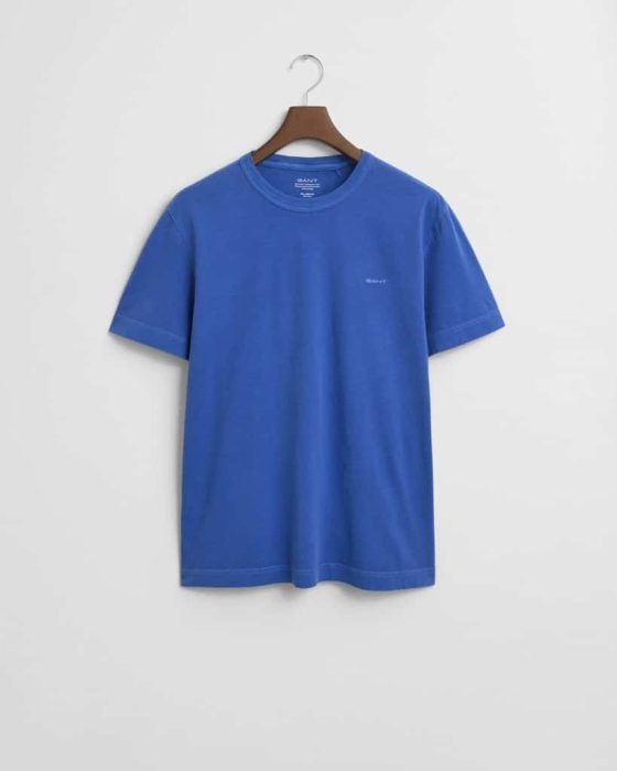 A plain blue T-shirt on a wooden hanger against a white background. The shirt has a small, subtle logo on the chest and a classic crew neck design.