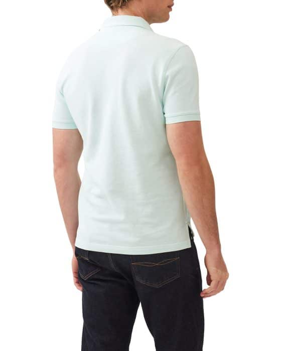 Man wearing a light mint green polo shirt and dark jeans, facing away.