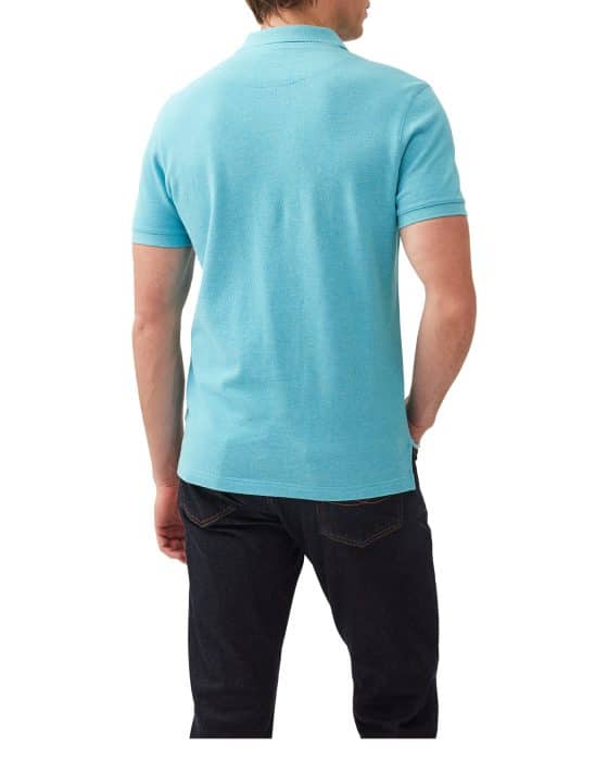 A person wearing a light blue polo shirt and dark jeans is standing with their back to the camera.