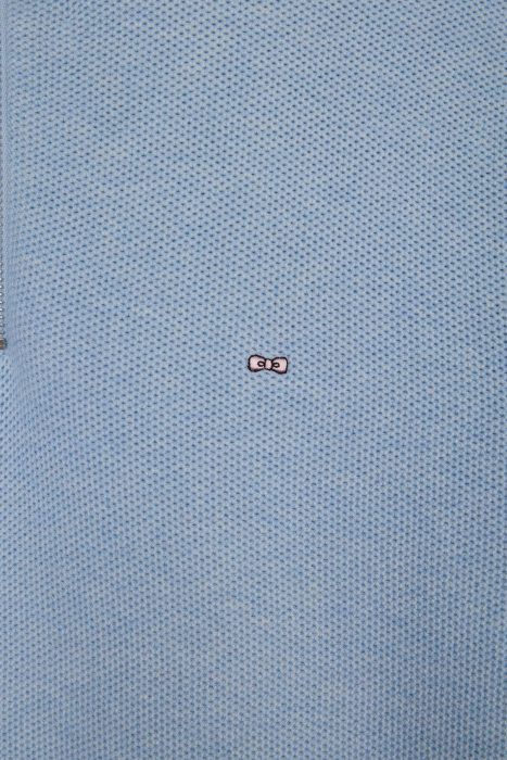 Close-up of a light blue textured fabric with a small embroidered design depicting eyes in the center.