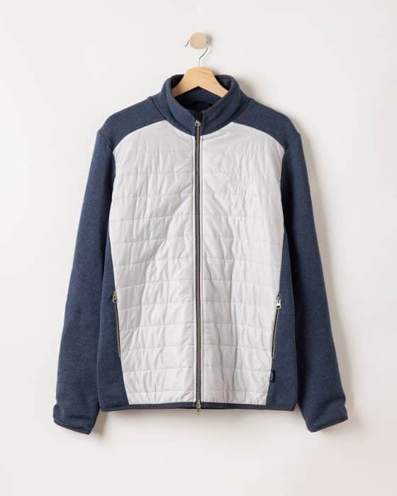 A jacket with a gray front and dark blue sleeves and back hangs on a wooden hanger against a plain white background. It features a zip-up front and two zippered pockets.