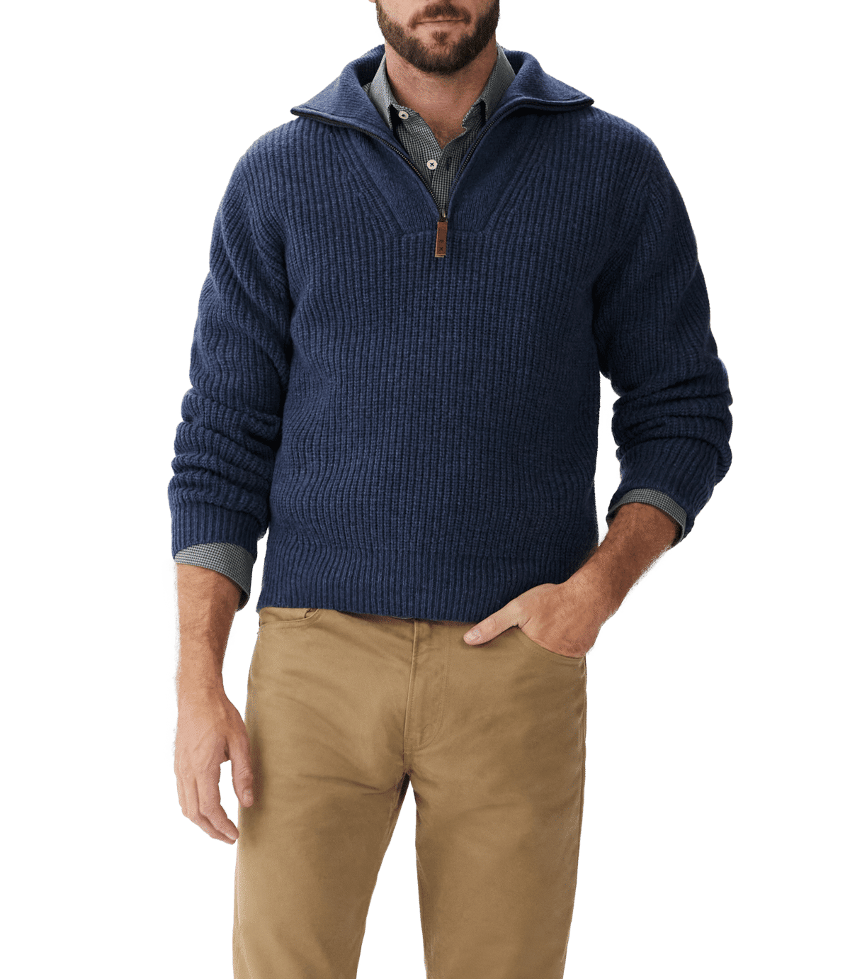 A man wearing a dark blue quarter-zip sweater over a collared shirt and tan pants stands with one hand in his pocket against a plain background.