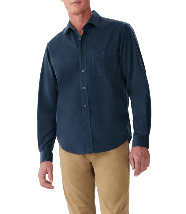 A man wearing a dark blue button-up shirt with a chest pocket and tan pants, standing against a plain background. His head is partially out of the frame.