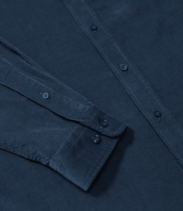 Close-up of a dark blue corduroy shirt, showing the fabric texture, buttons, and part of the sleeve with buttoned cuffs.