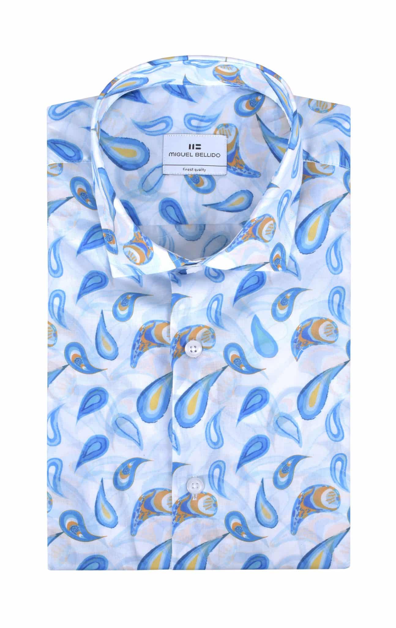 A folded, long-sleeve dress shirt with a light blue background and a colorful paisley pattern in blue, yellow, and orange. The shirt has a classic collar and white buttons, with a visible brand label inside the collar.