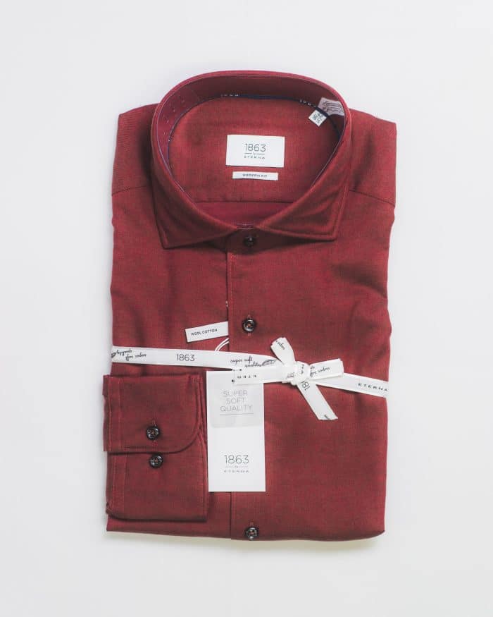 A neatly folded maroon dress shirt with black buttons, labeled 1863 and Super Quality, tied with a white branded ribbon, displayed on a white background.
