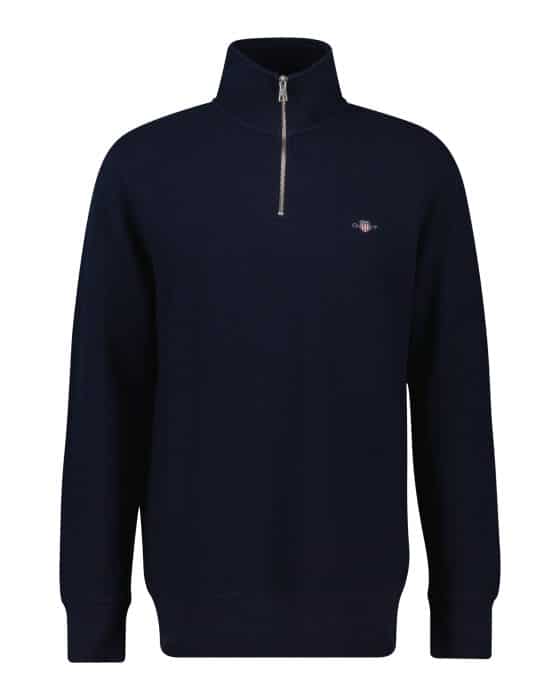 A navy blue quarter-zip pullover sweater with a high collar, long sleeves, and a small embroidered logo on the left chest. The sweater has ribbed cuffs and hem.