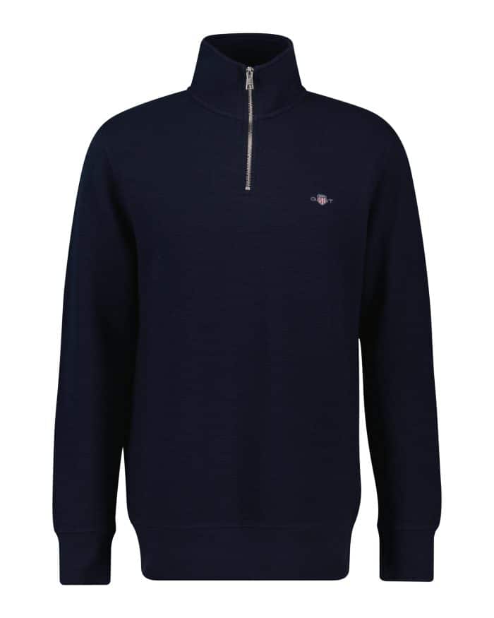 A navy blue quarter-zip pullover sweater with a high collar, long sleeves, and a small embroidered logo on the left chest. The sweater has ribbed cuffs and hem.
