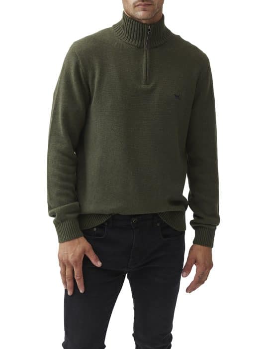 A person wearing an olive green quarter-zip sweater with a ribbed collar and cuffs, paired with black jeans. The sweater has a small embroidered logo on the chest. The person’s head is not visible.