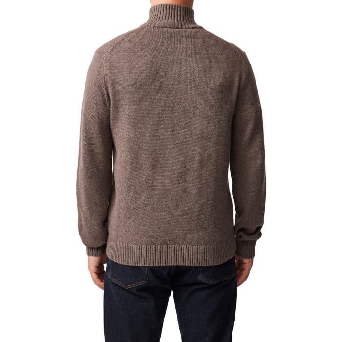 A person wearing a brown, long-sleeve, high-collar sweater and dark blue jeans, shown from the back against a white background.