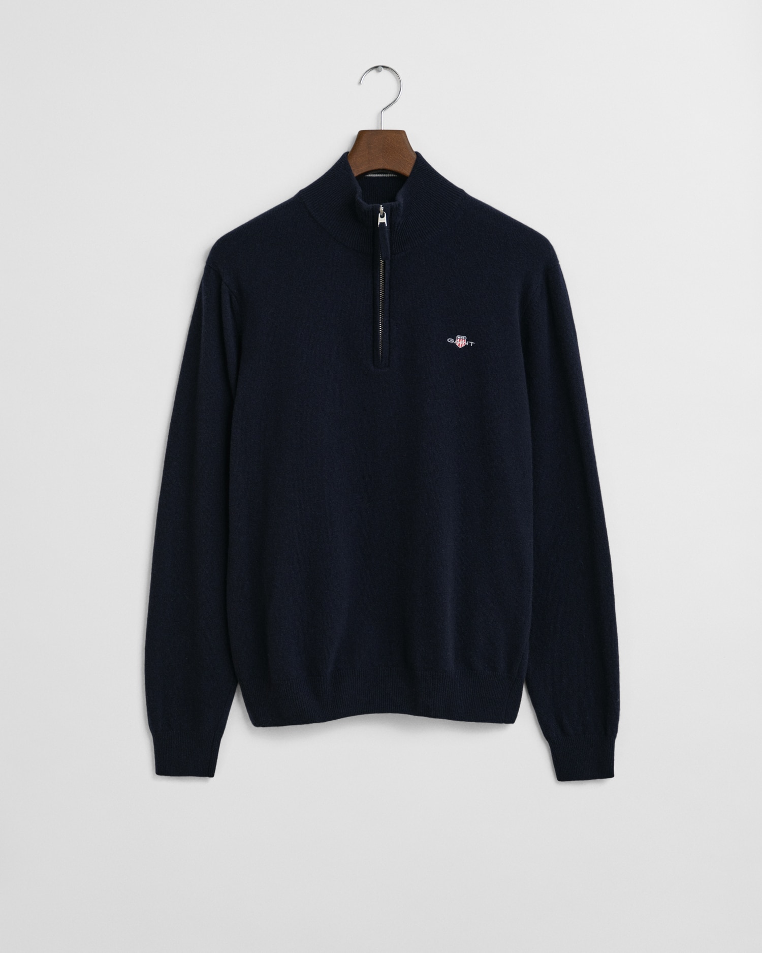 A navy blue quarter-zip sweater with a small embroidered logo on the left chest, hanging on a wooden hanger against a plain white background.