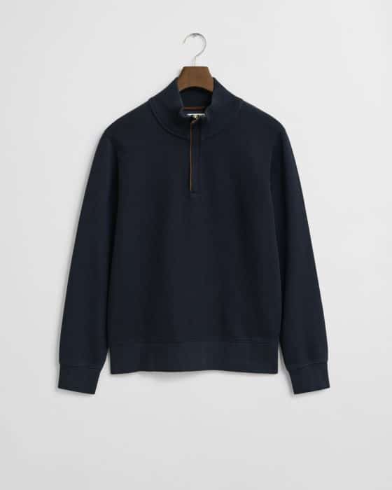 A navy blue quarter-zip pullover sweatshirt with a high collar, hanging on a wooden hanger against a plain white background.