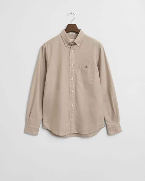 A beige long-sleeve button-up shirt with a collar and a chest pocket, hanging on a hanger against a plain white background.