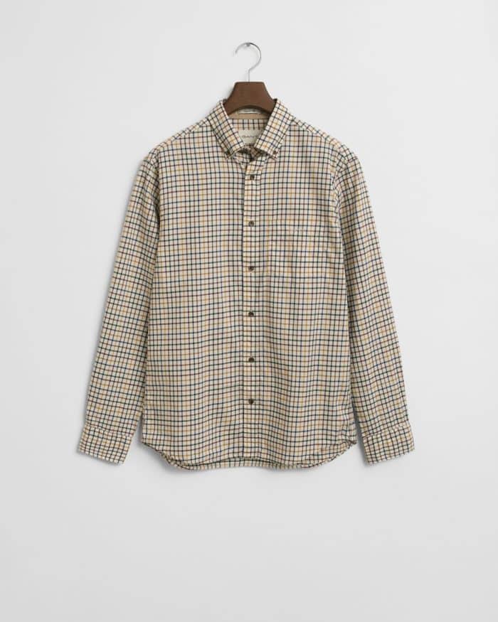 A long-sleeve button-up shirt with a beige, navy, and brown checkered pattern hangs on a wooden hanger against a plain white background.