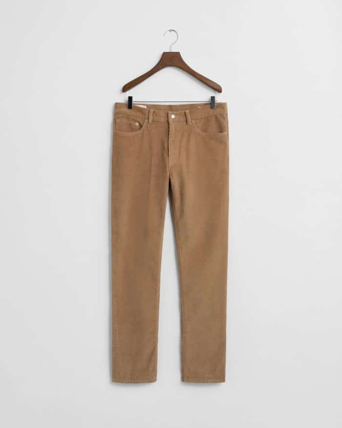 A pair of tan corduroy pants with front and back pockets hangs on a wooden hanger against a plain white background.