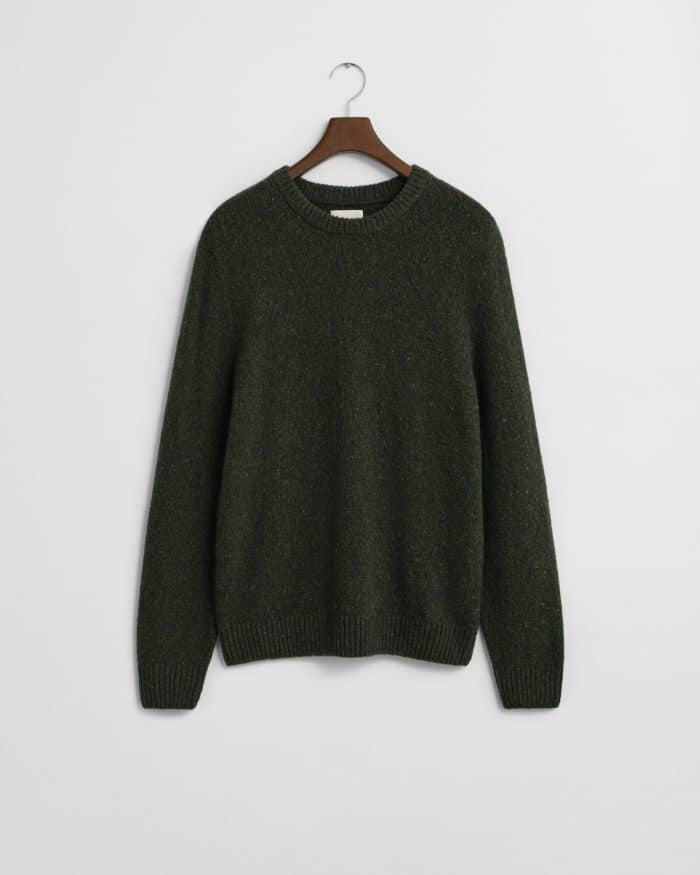 A dark green knit sweater with long sleeves and a round neckline, hanging on a wooden hanger against a plain white background.
