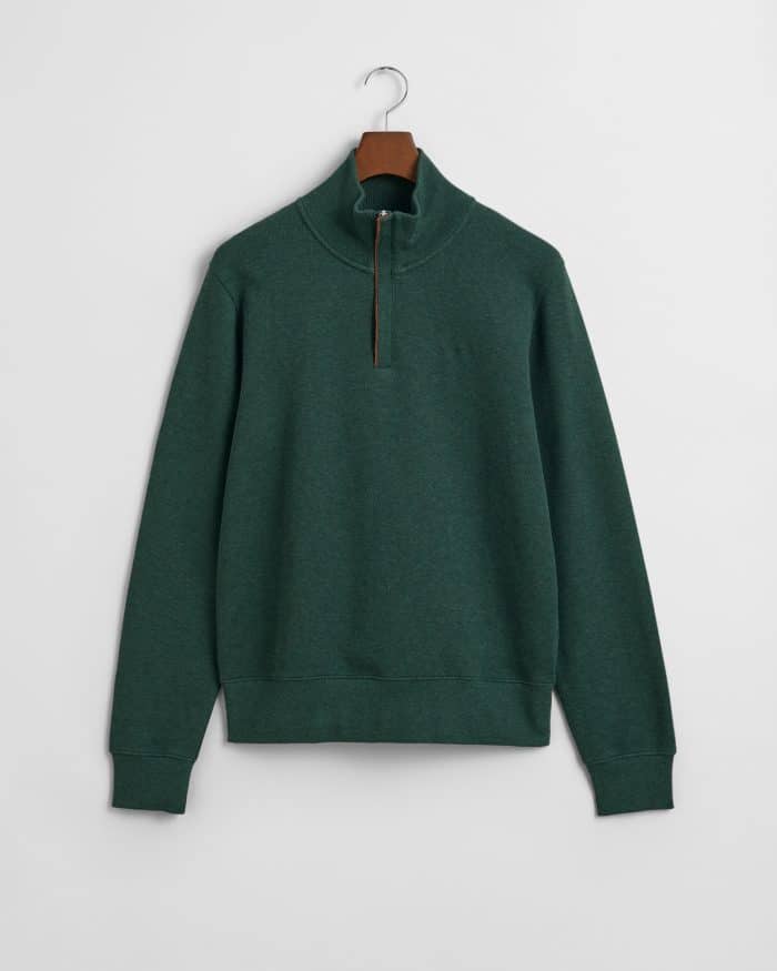 A dark green quarter-zip pullover with a stand-up collar, long sleeves, ribbed cuffs, and hem, displayed on a hanger against a plain white background.