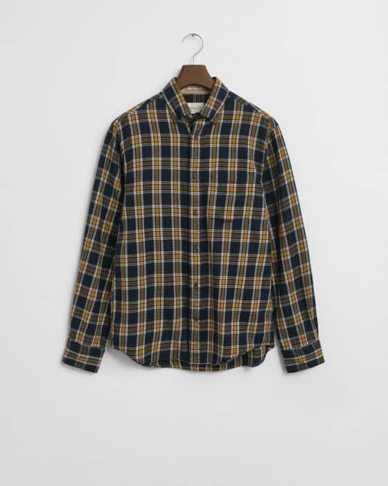 A long-sleeve button-up shirt with a blue, yellow, and white plaid pattern hangs on a wooden hanger against a plain white background.