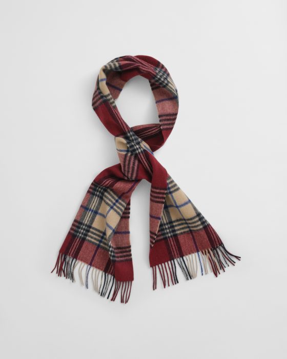 A wool scarf with a classic plaid pattern in red, beige, black, and white, neatly folded with fringed ends displayed against a plain white background.