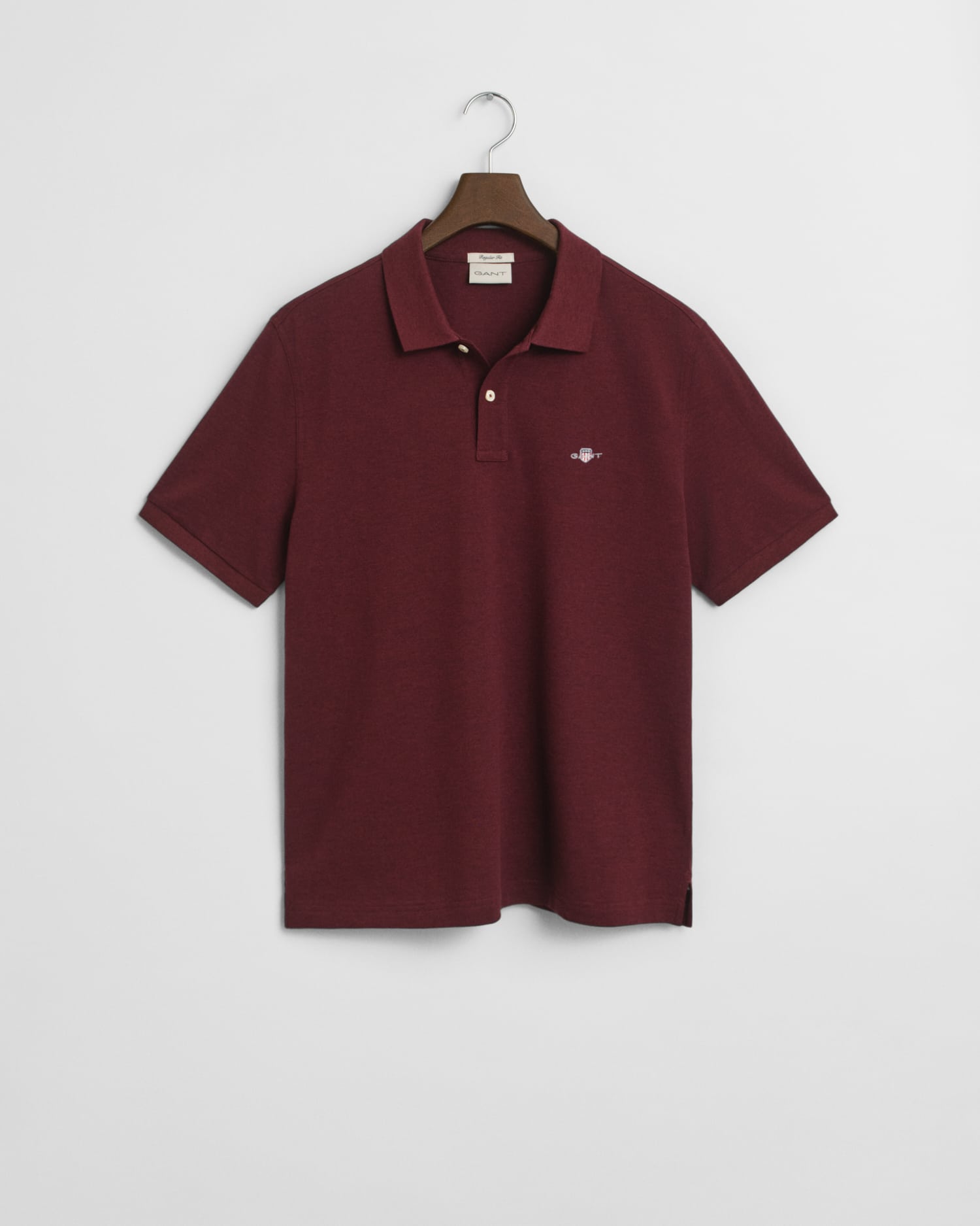 A maroon short-sleeve polo shirt with a collar, two buttons, and a small embroidered logo on the left chest, hanging on a hanger against a white background.