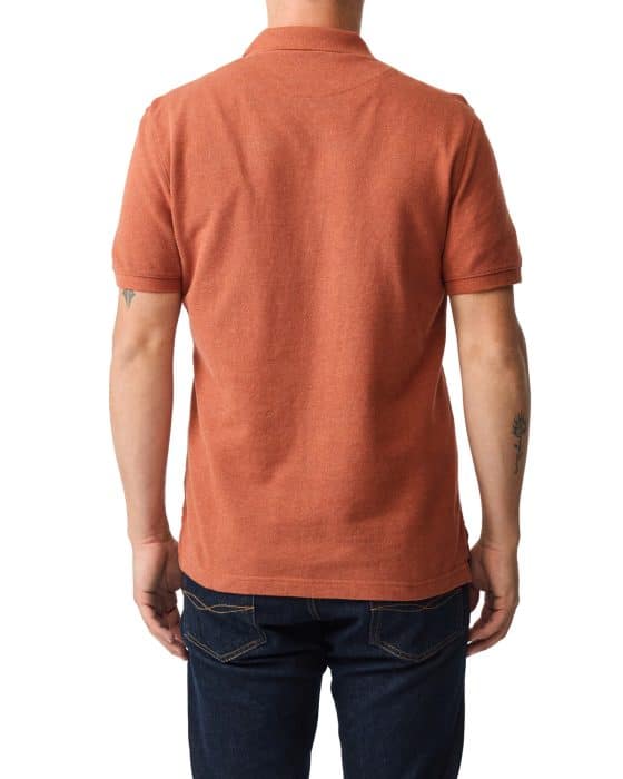 A person wearing a short-sleeve, rust-colored polo shirt and dark jeans, shown from the back. The person has short hair and visible tattoos on both arms. The background is white.