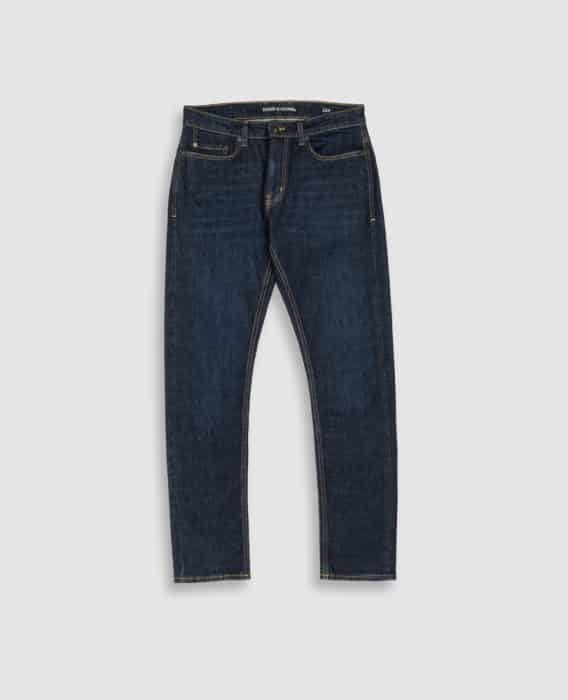 A pair of dark blue denim jeans with a slim fit, classic five-pocket design, and visible tan stitching, displayed against a light gray background.