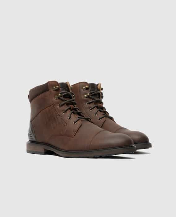A pair of brown leather lace-up boots with dark soles and ankle padding, displayed on a light gray background.