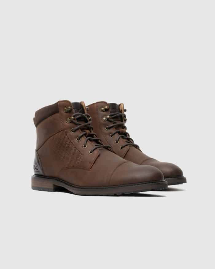A pair of brown leather lace-up boots with dark soles and ankle padding, displayed on a light gray background.