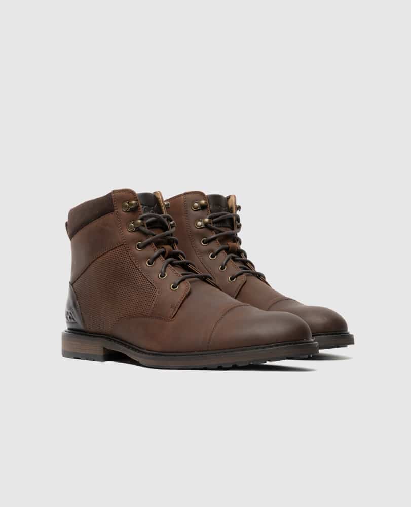 A pair of brown leather lace-up boots with dark soles and ankle padding, displayed on a light gray background.