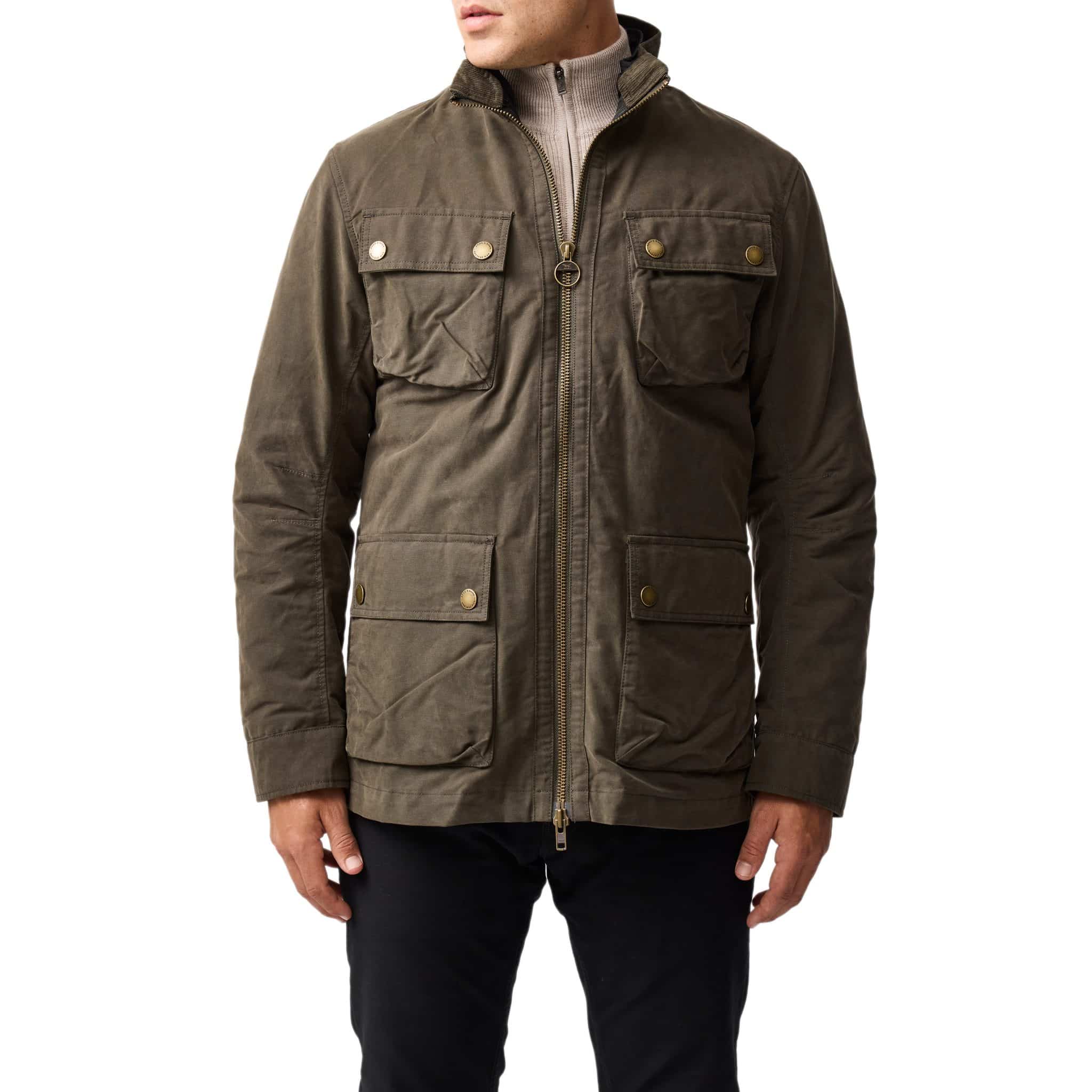 A person wearing a khaki green field jacket with a stand collar, zip and snap closures, and four front flap pockets, paired with black pants. The persons head is not visible.