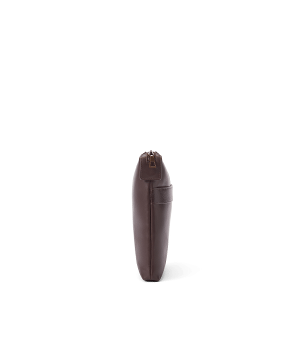 A slim, dark brown leather pouch stands upright on a white background, shown from the side with a visible zipper and a small handle.