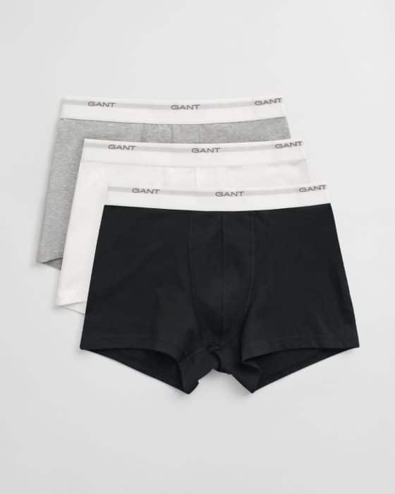 Three pairs of mens boxer briefs in black, white, and gray, each with a white waistband featuring the brand name GANT in gray text. The boxers are neatly stacked on a plain background.