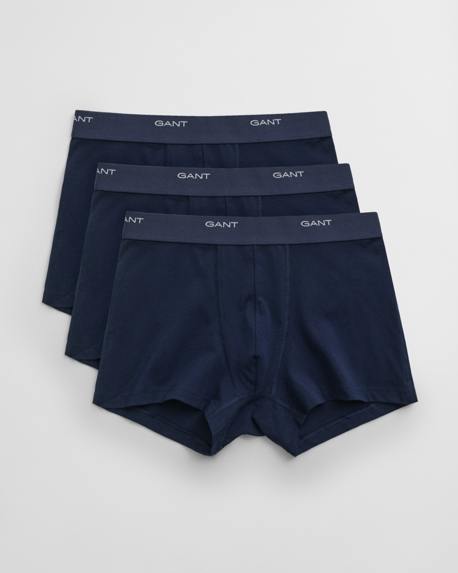 Three pairs of navy blue mens boxer briefs with elastic waistbands featuring the brand name GANT in white text, arranged in a slightly overlapping, fanned-out pattern on a white background.