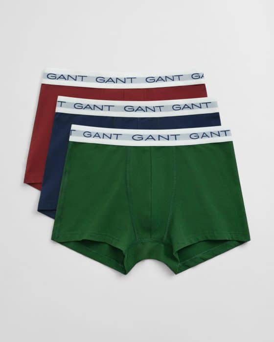 Three pairs of mens boxer briefs in green, navy blue, and maroon, each with a white waistband featuring the word GANT in blue lettering, laid out overlapping on a white background.