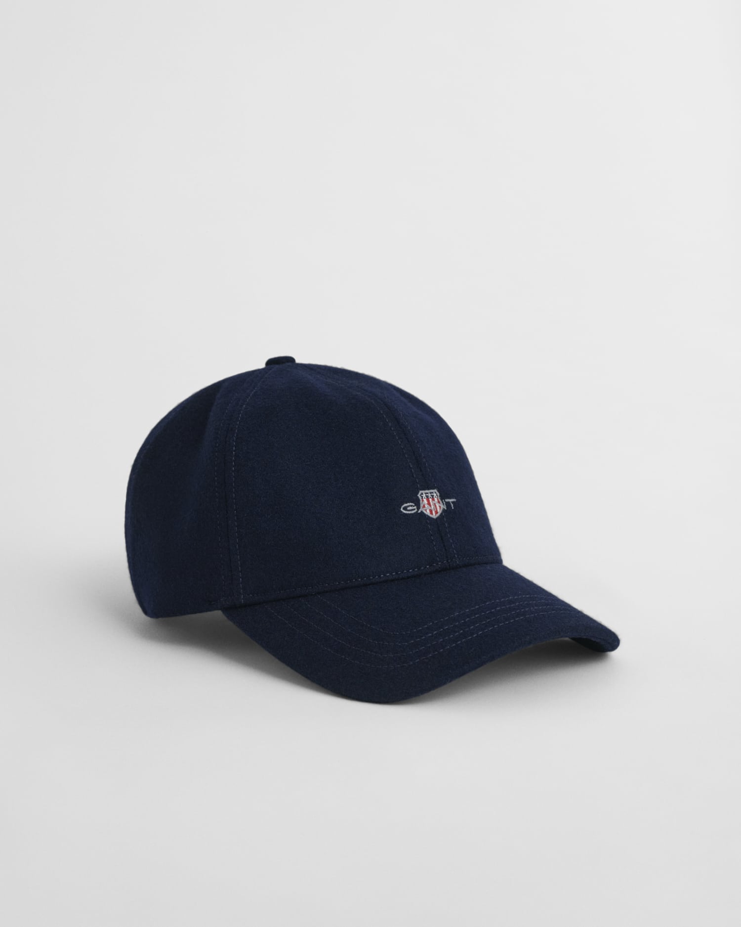 A navy blue baseball cap with a small embroidered shield logo and the word “GANT” on the front, displayed on a plain white background.