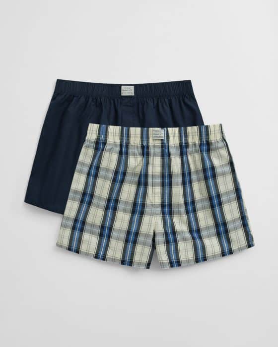 Two pairs of mens boxers: one solid navy blue, and one with a blue, black, and white plaid pattern, both with elastic waistbands and displayed on a plain white background.