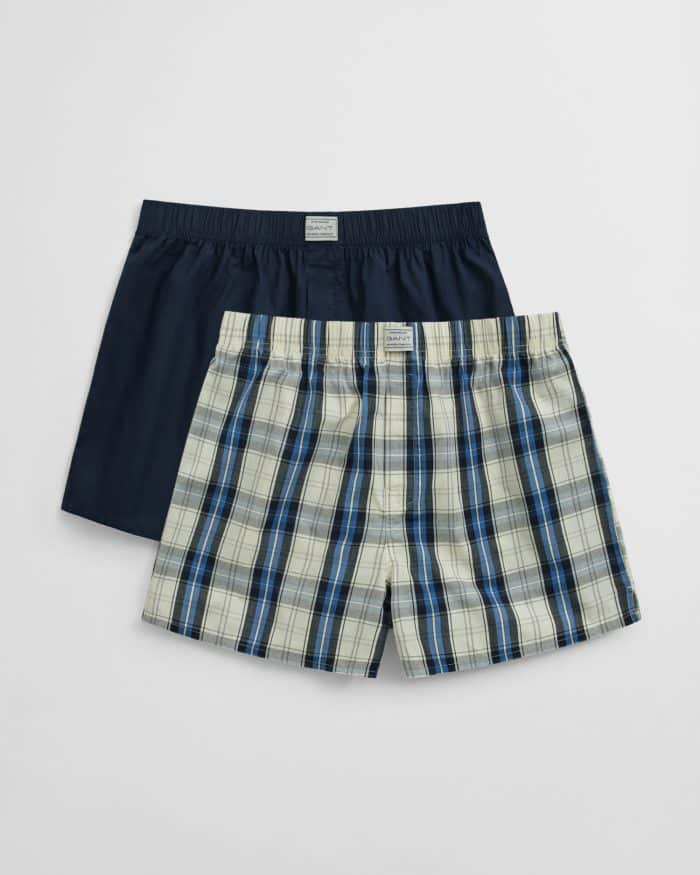 Two pairs of mens boxers: one solid navy blue, and one with a blue, black, and white plaid pattern, both with elastic waistbands and displayed on a plain white background.