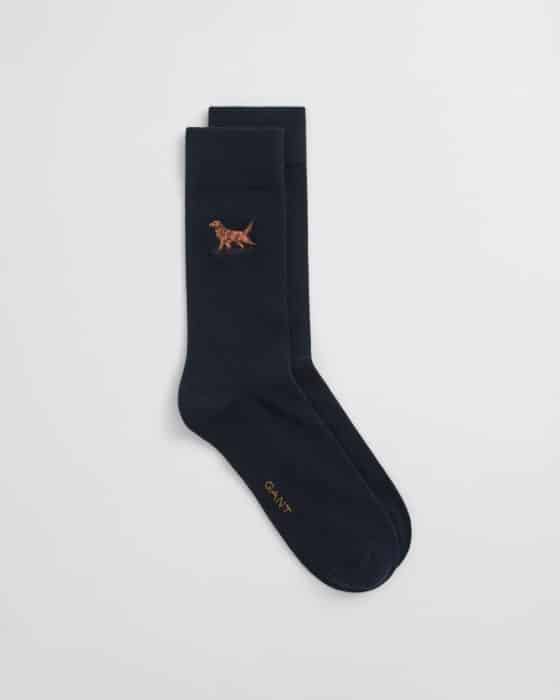 A pair of dark navy blue socks with a small embroidered brown dog near the top and the brand name GANT in gold lettering near the toe. The socks are laid flat on a white background.