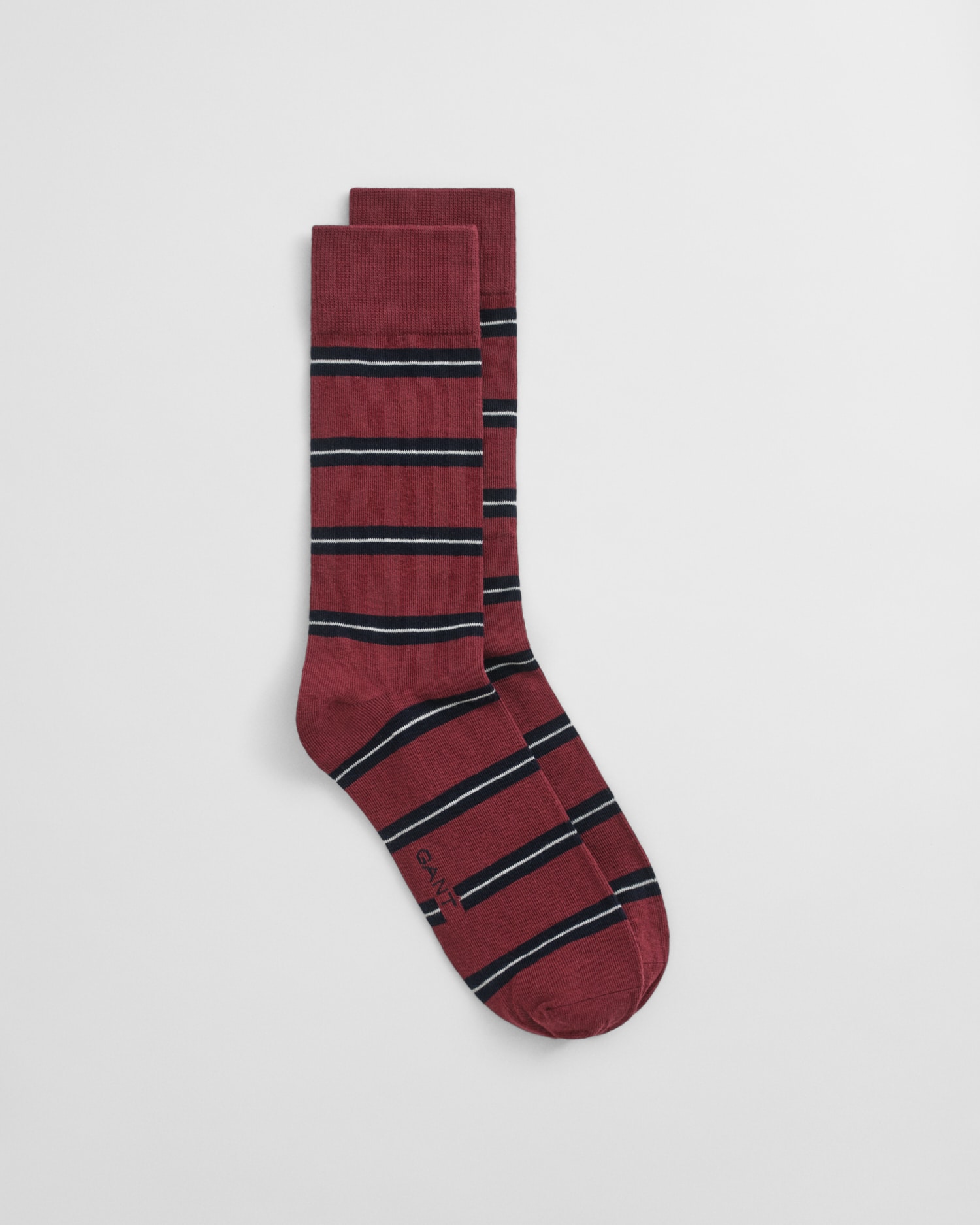A pair of maroon socks with horizontal black and white stripes, laid flat on a white background.