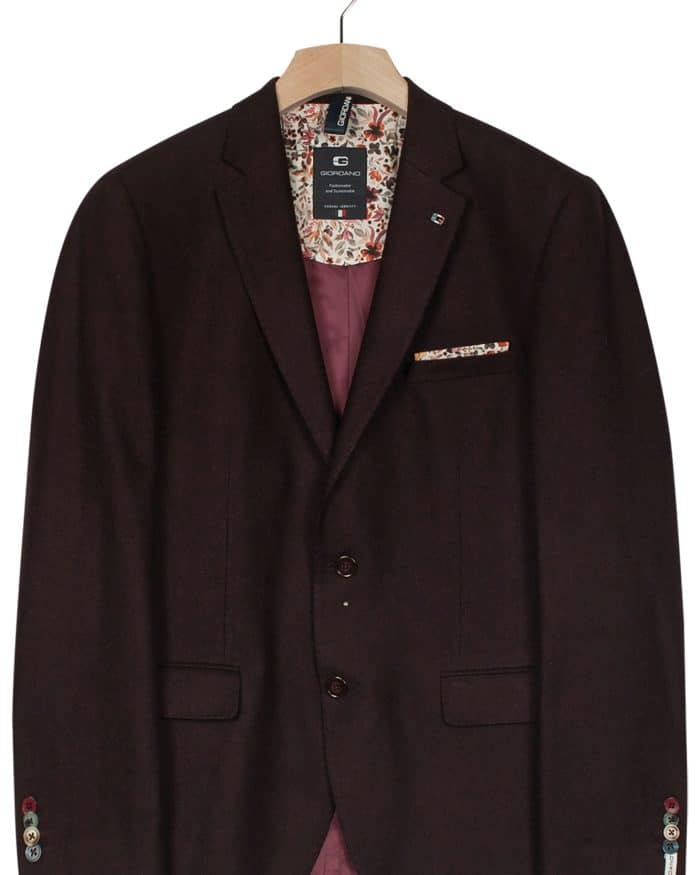 A dark burgundy mens blazer on a wooden hanger, featuring a floral inner lining, two front buttons, a chest pocket with a patterned handkerchief, and button details on the sleeves.