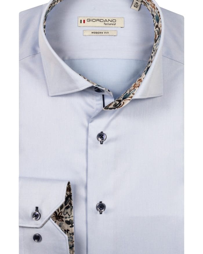 A light blue long-sleeve dress shirt with a modern fit, folded neatly. The inner collar and cuffs feature a floral pattern. The shirt has dark buttons and a Giordano Tailored label on the inside collar.