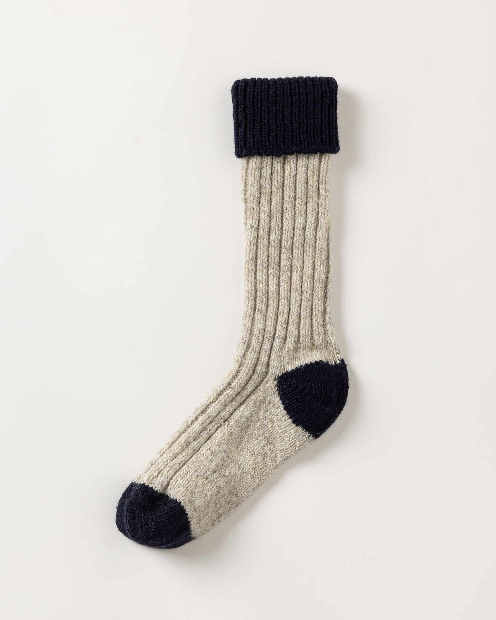 A single ribbed wool sock with a beige body and contrasting dark navy heel, toe, and cuff, displayed on a plain white background.