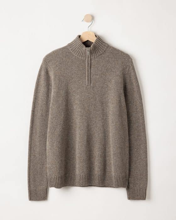 A light brown, long-sleeved knit sweater with a high collar and a partial zipper, hanging on a wooden hanger against a plain white background.