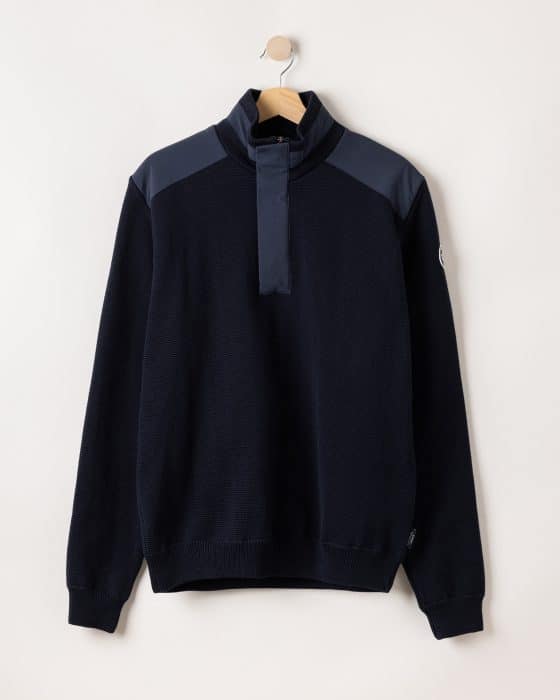 A dark navy long-sleeve pullover with a high collar, buttoned placket, and contrasting dark blue shoulder panels, displayed on a wooden hanger against a light background.