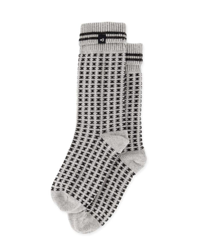 A pair of gray socks with a black checkered pattern and black stripes near the top, neatly stacked on a white background.