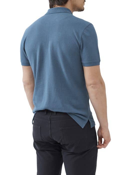 A man is standing with his back to the camera, wearing a short-sleeved teal polo shirt and black pants. His arms are relaxed at his sides, and the photo is taken against a plain white background.